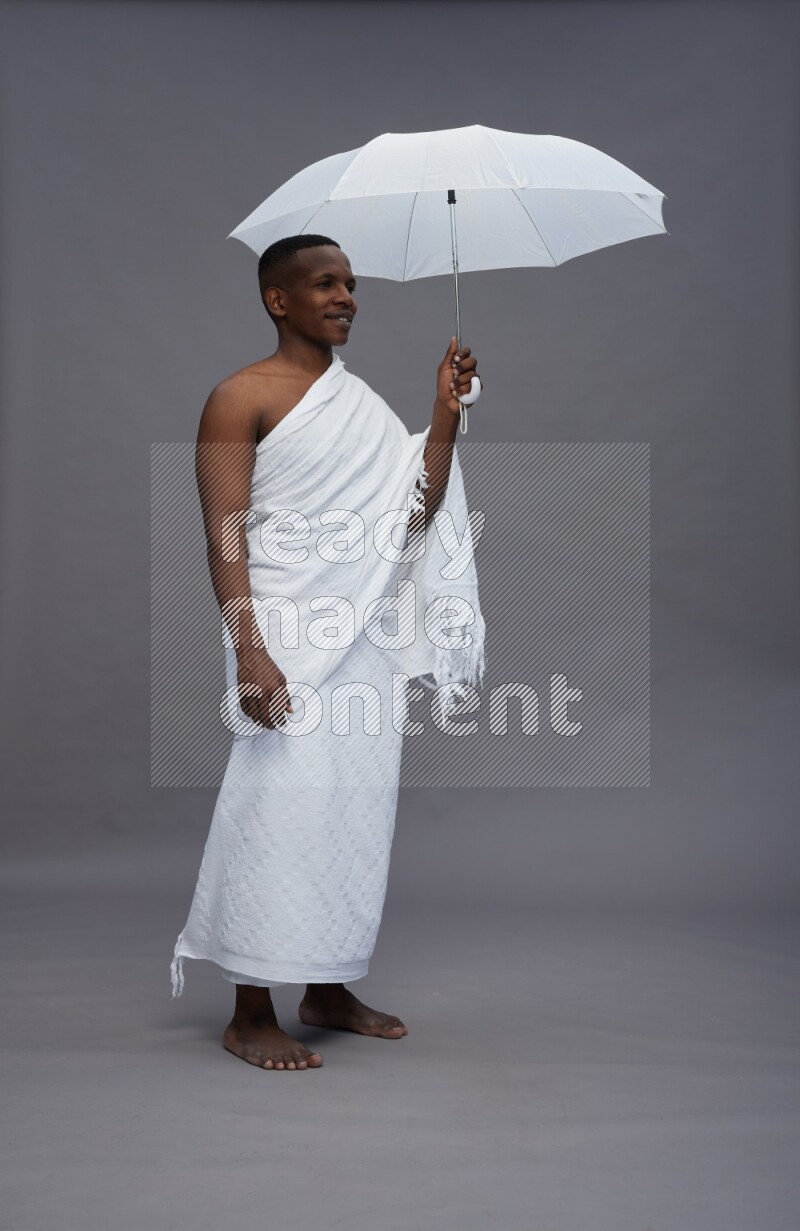 A man wearing Ehram Standing holding umbrella on gray background