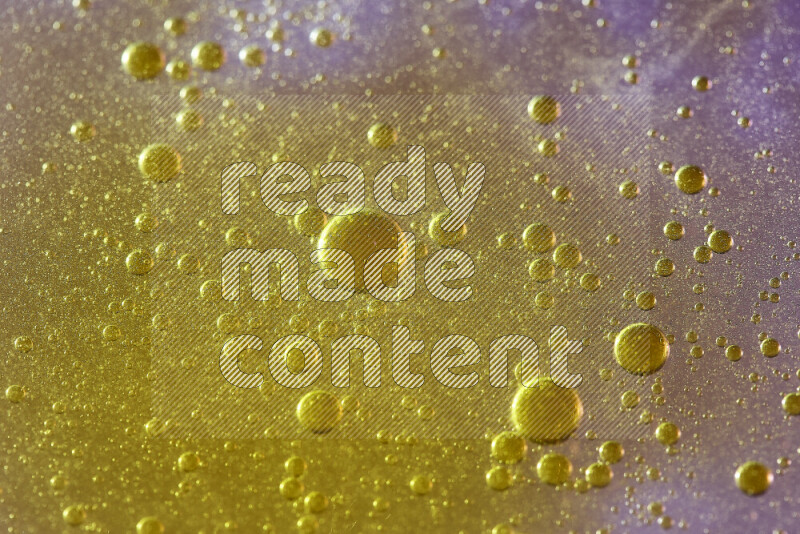 Close-ups of abstract yellow watercolor drops on oil Surface on pink background