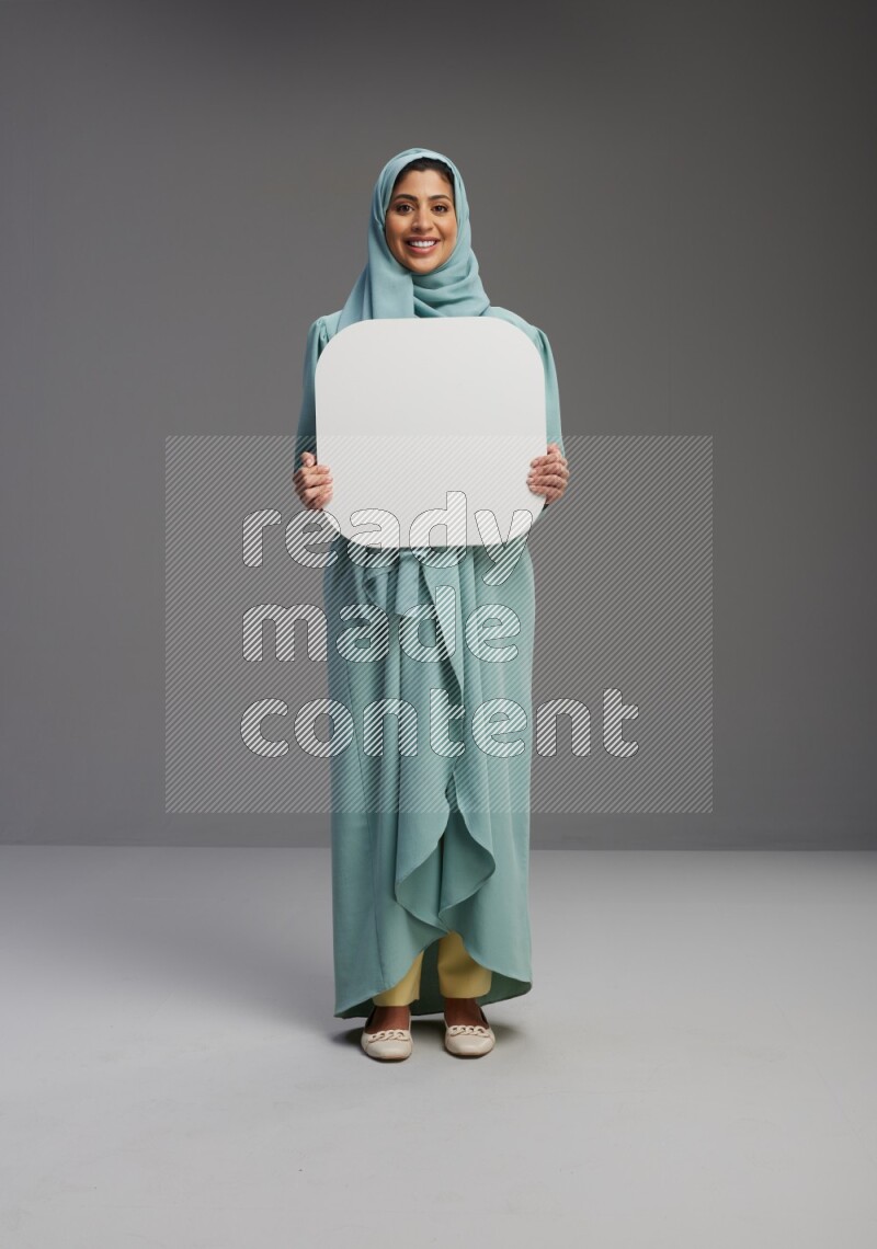 Saudi Woman wearing Abaya standing holding social media sign on Gray background
