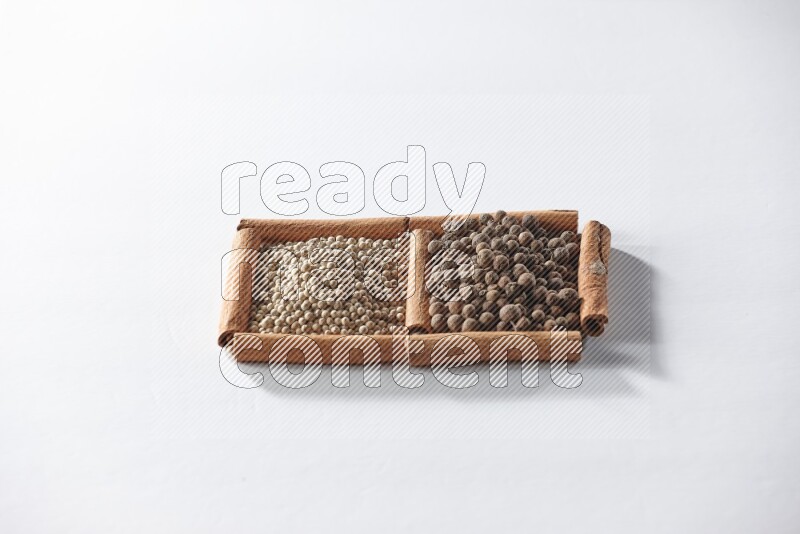 2 squares of cinnamon sticks full of white pepper and allspice on white flooring