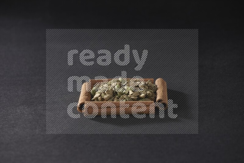 A single square of cinnamon sticks full of Cardamom on black flooring