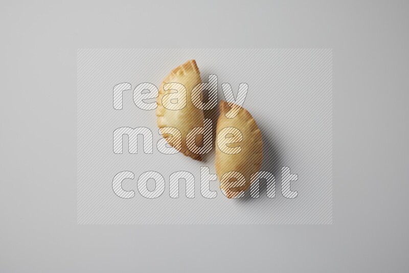 Two fried sambosa from a top angle on a white background