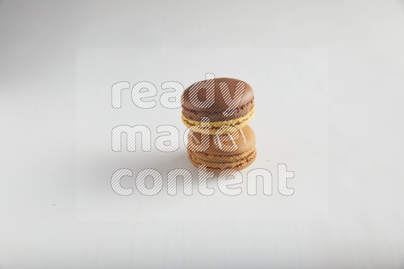 45º Shot of of two assorted Brown Irish Cream, and Yellow, and Brown Chai Latte macarons on white background