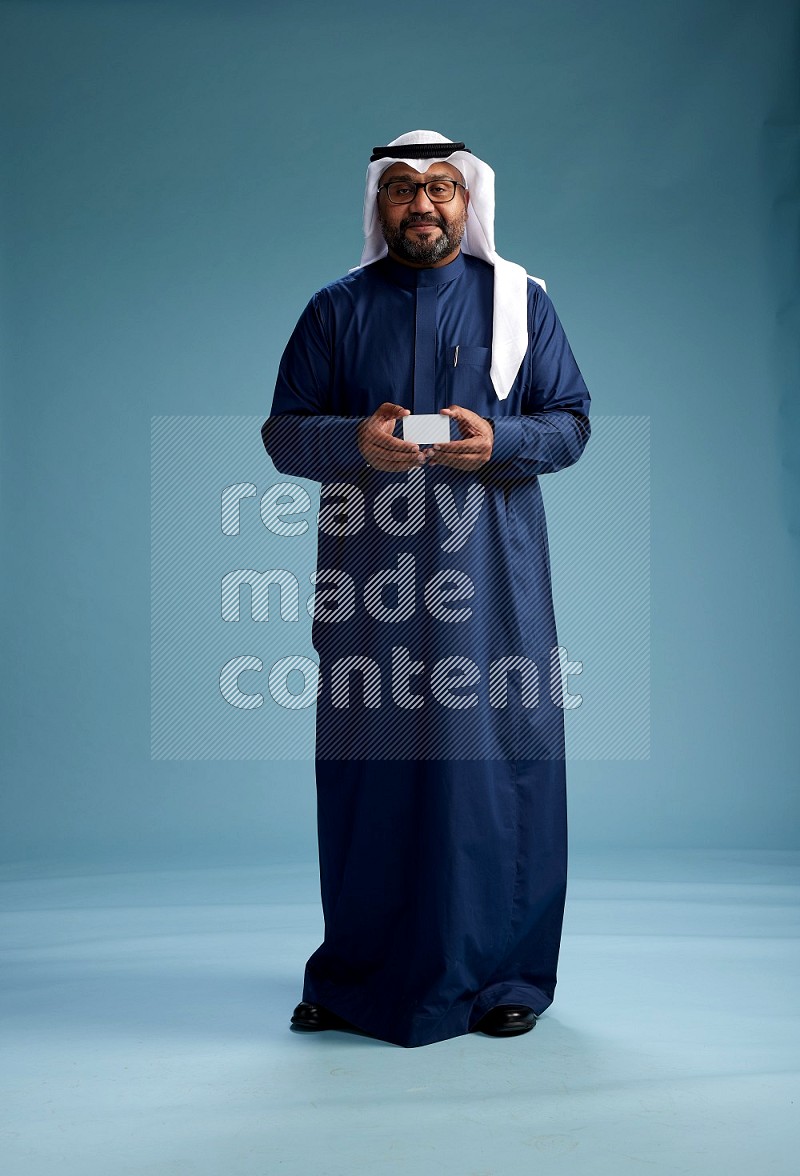 Saudi Man with shimag Standing holding ATM on blue background
