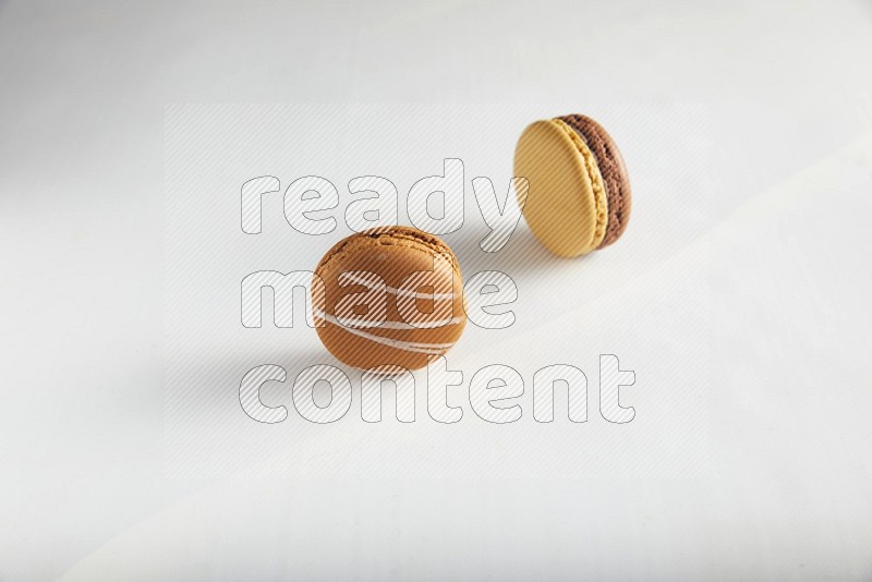 45º Shot of of two assorted Brown Irish Cream, and Yellow, and Brown Chai Latte macarons on white background