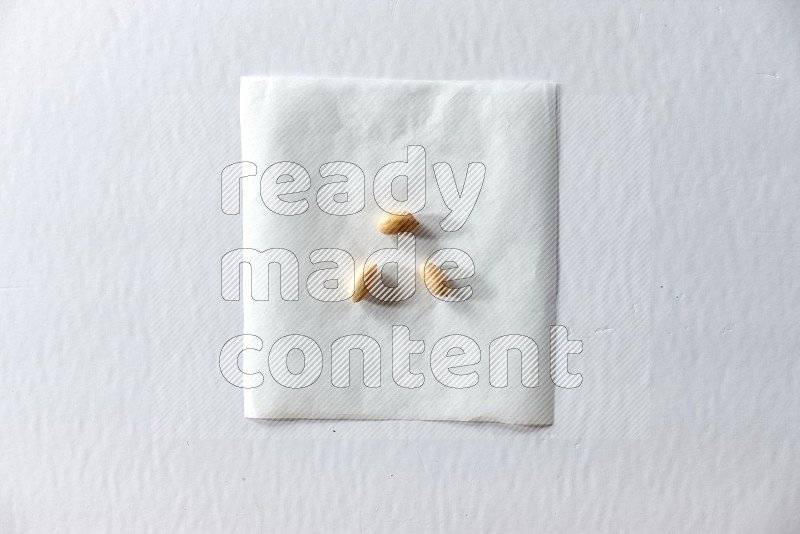 3 peeled peanuts on a piece of paper on a white background in different angles