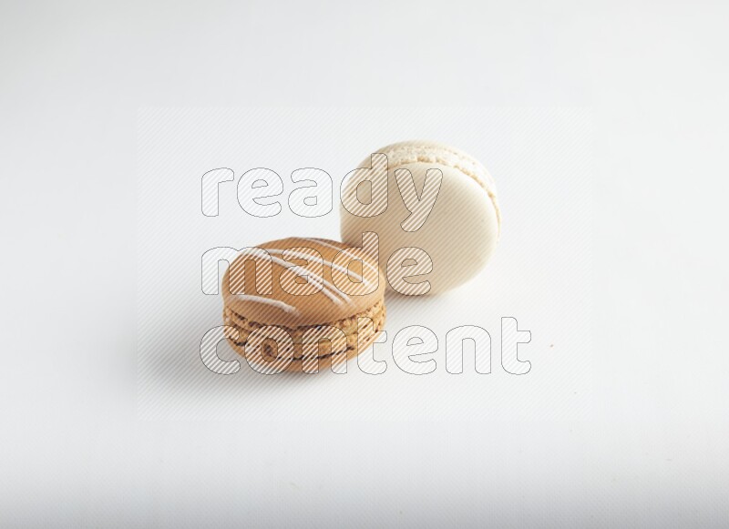 45º Shot of of two assorted Brown Irish Cream, and White Caramel fleur de sel macarons on white background