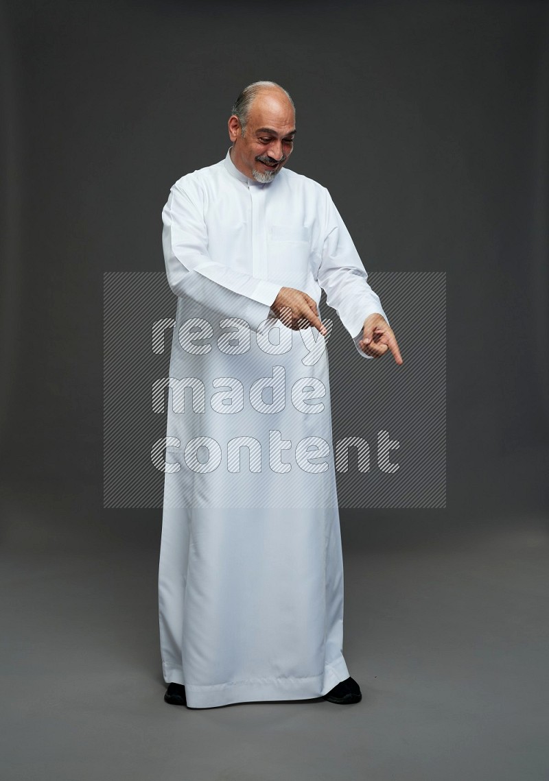 Saudi man without shomag Standing Interacting with the camera on gray background