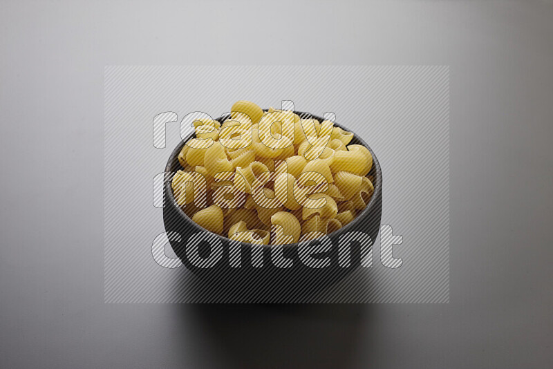 Pipe pasta in a pottery bowl on grey background
