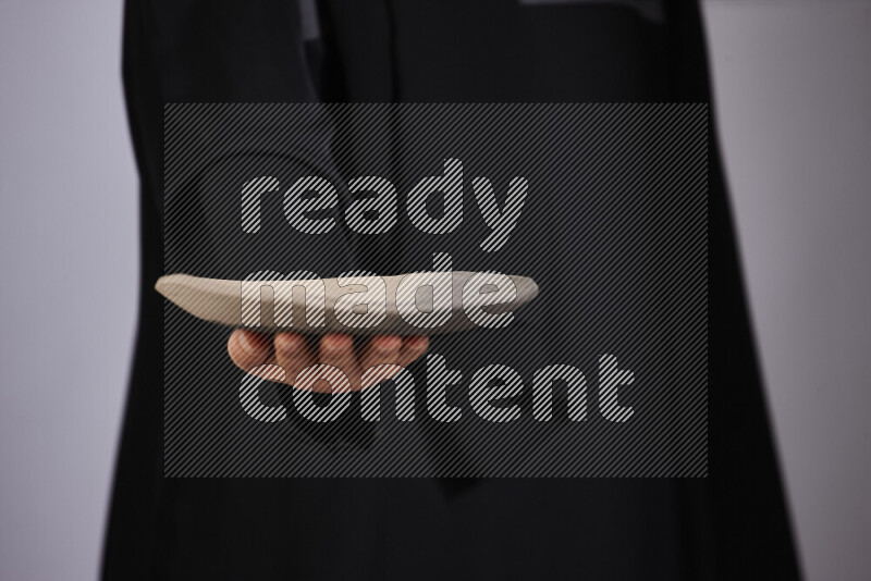 A woman in black abaya holding different pottery essentials in different positions