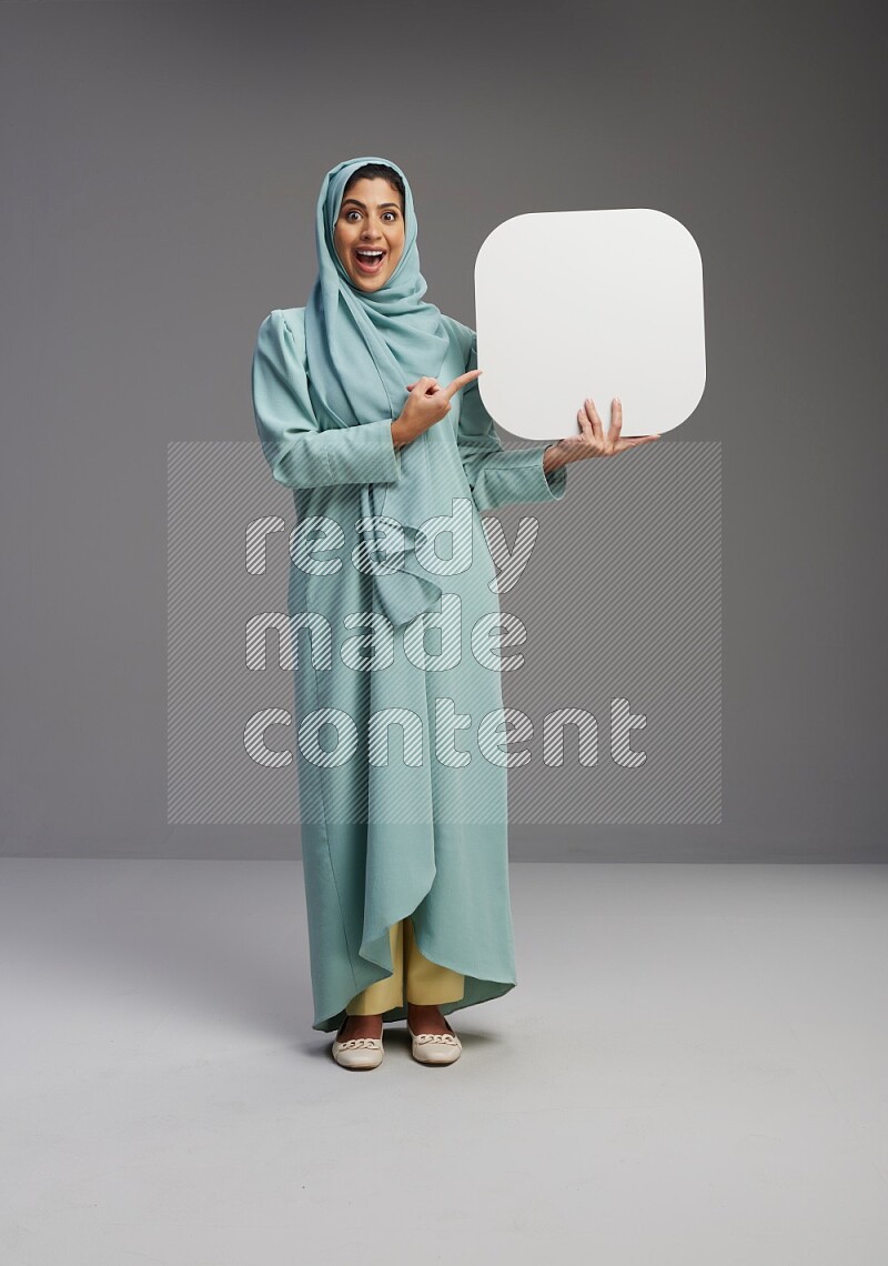 Saudi Woman wearing Abaya standing holding social media sign on Gray background