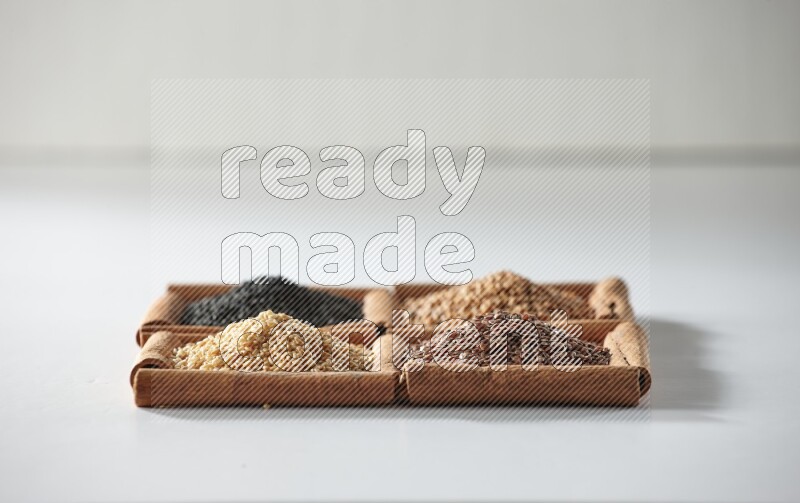 4 squares of cinnamon sticks full of black seeds, mustard seeds, flaxseeds and sesame on white flooring