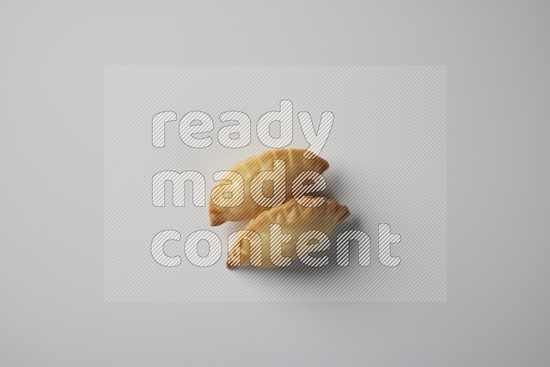 Two fried sambosa from a top angle on a white background