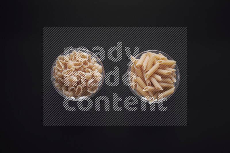 Different pasta types in glass bowls on black background