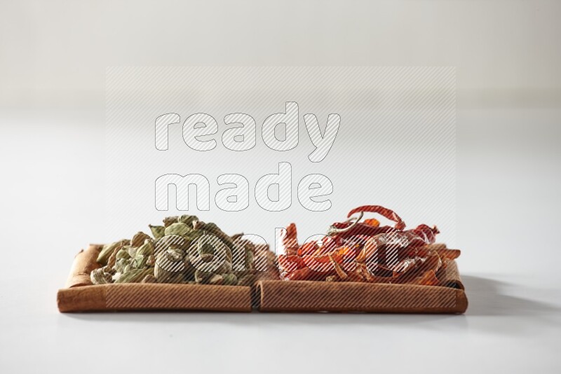 مربعان من أعواد القرفة ممتلئان بحبوب الهيل والفلفل الحار المجفف علي خلفية بيضاء