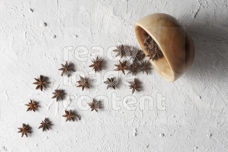 Star anise lined out of wooden plate across the frame on white background