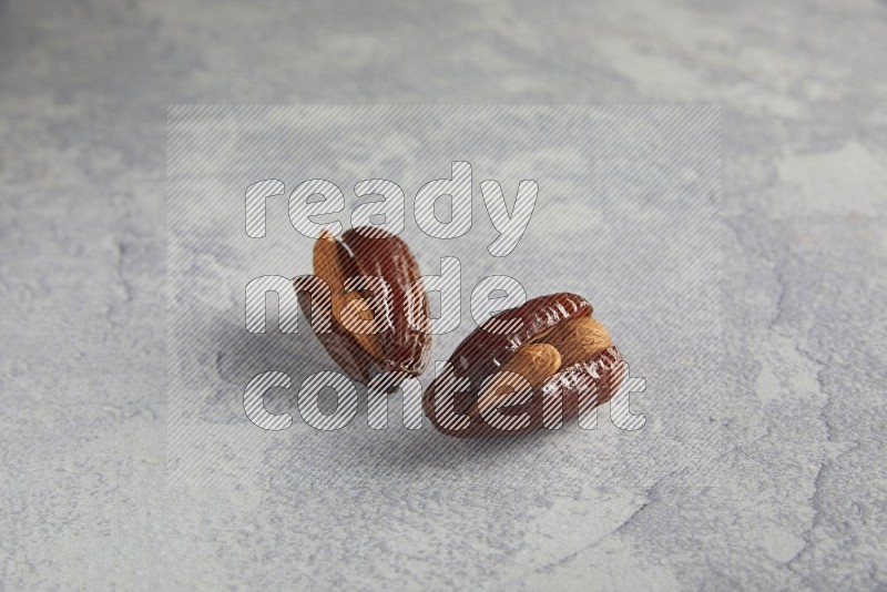 Two Almond stuffed date on a light grey background