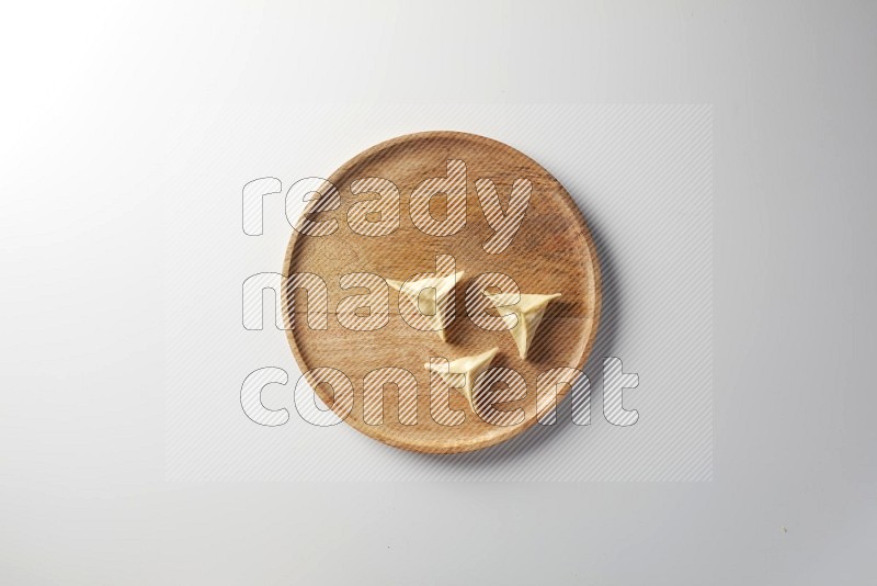 Three Sambosas on a wooden round plate on a white background