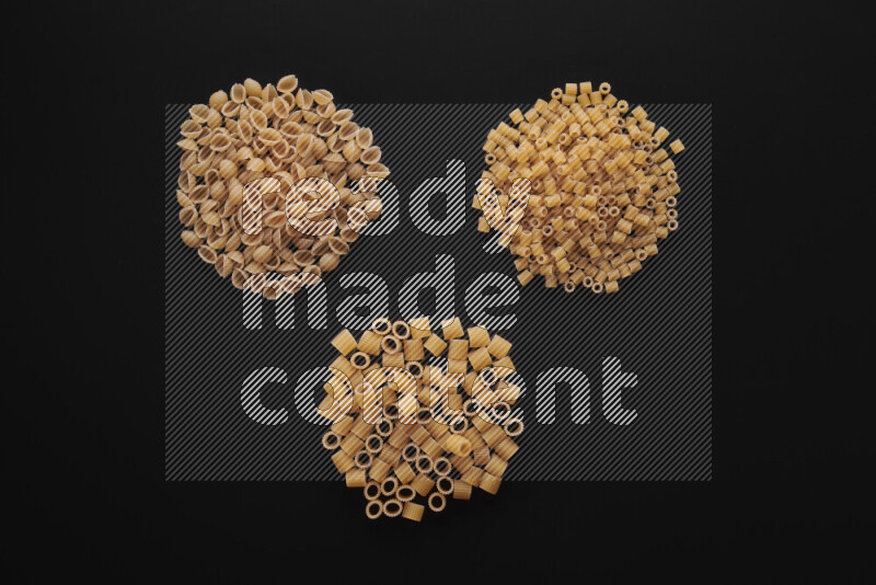 Different pasta types in bunches on black background