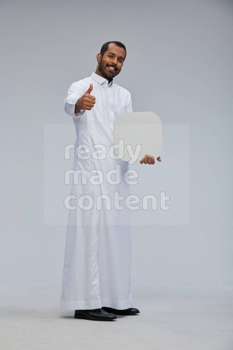 Saudi man wearing Thob standing holding social media sign on Gray background
