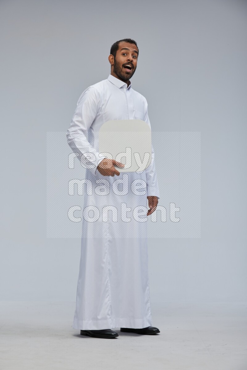 Saudi man wearing Thob standing holding social media sign on Gray background