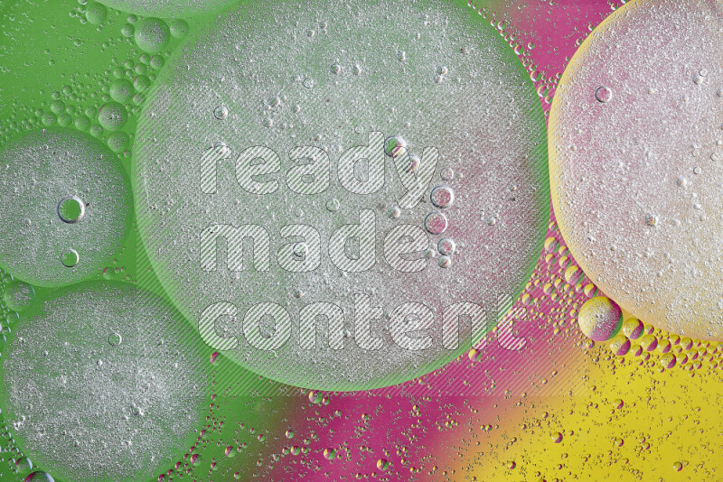 Close-ups of abstract oil bubbles on water surface in shades of yellow, green and pink
