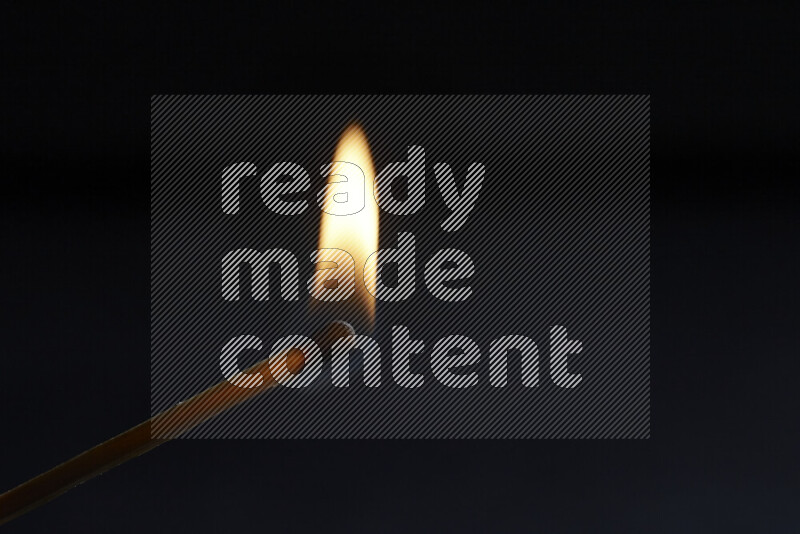 A burning matchstick isolated on dark backdrop