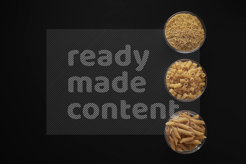 Different pasta types in 3 glass bowls on black background