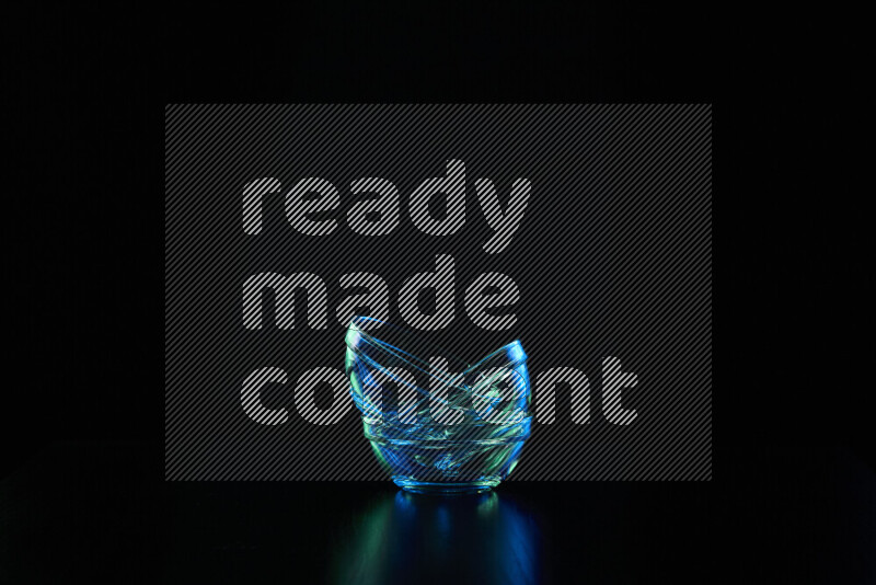 Glassware with rim light in blue and green against black background