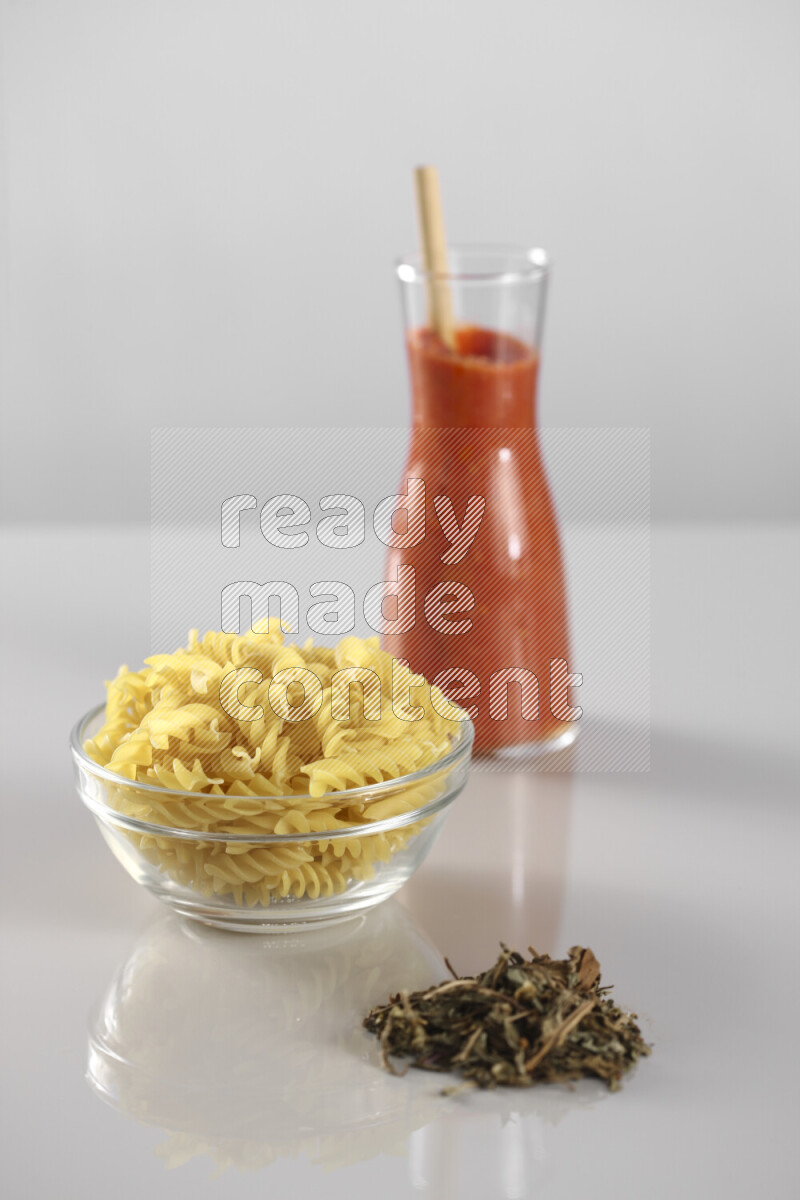 معكرونة مع صلصة طماطم مع مكونات متنوعة من الطماطم والثوم والريحان والفلفل الأحمر والفلفل الأسود والفلفل الأبيض وأوراق الغار والهيل وسنابل القمح على خلفية رمادية