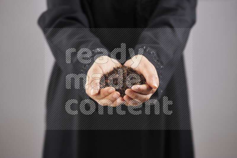Woman in abaya holding different kinds of spices in different positions