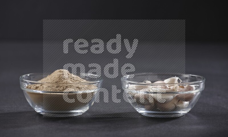 وعاءان زجاجيان احدهما ممتلئ ببودرة الثوم والأخر ممتلئ بفصوص الثوم علي خلفية سوداء