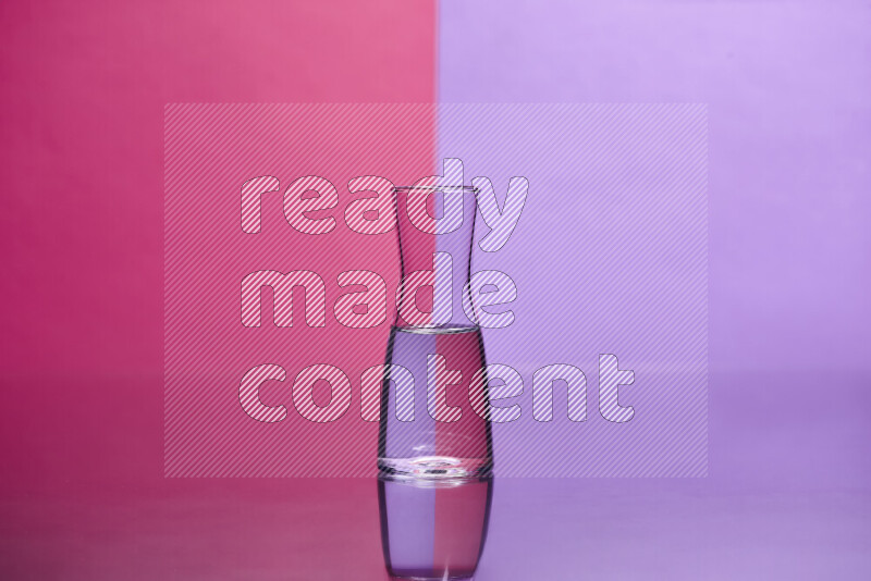 The image features a clear glassware filled with water, set against pink and light purple background