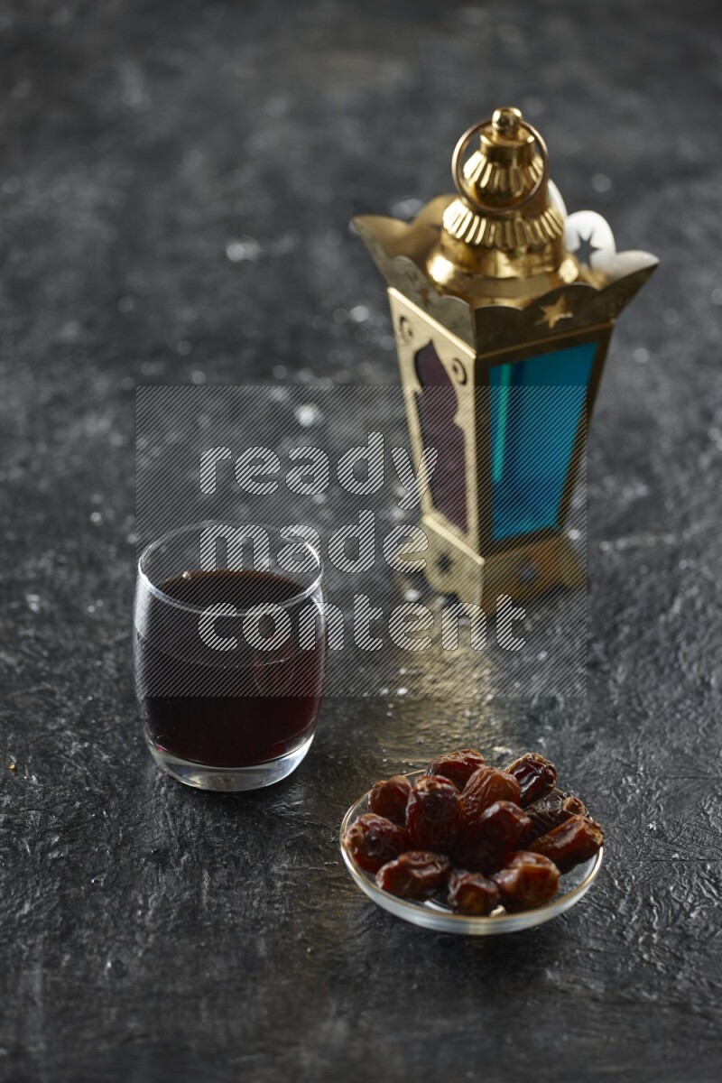 A golden lantern with different drinks, dates, nuts, prayer beads and quran on textured black background