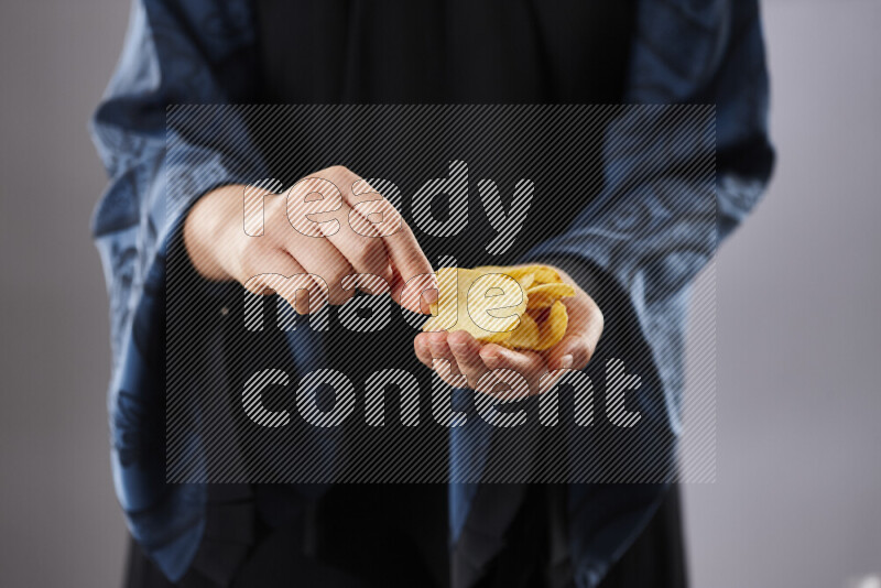 Woman in abaya holding different kinds of snacks in different positions