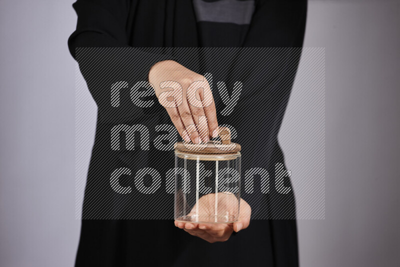 A woman in black abaya holding different glassware in different positions