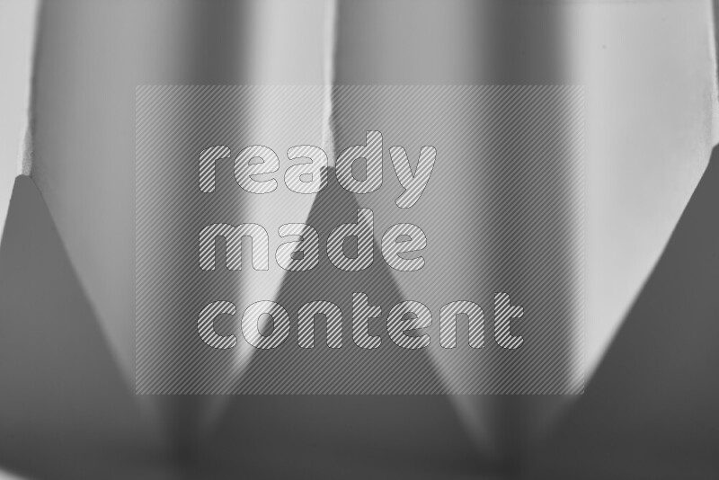 A close-up abstract image showing sharp geometric paper folds in grey gradients