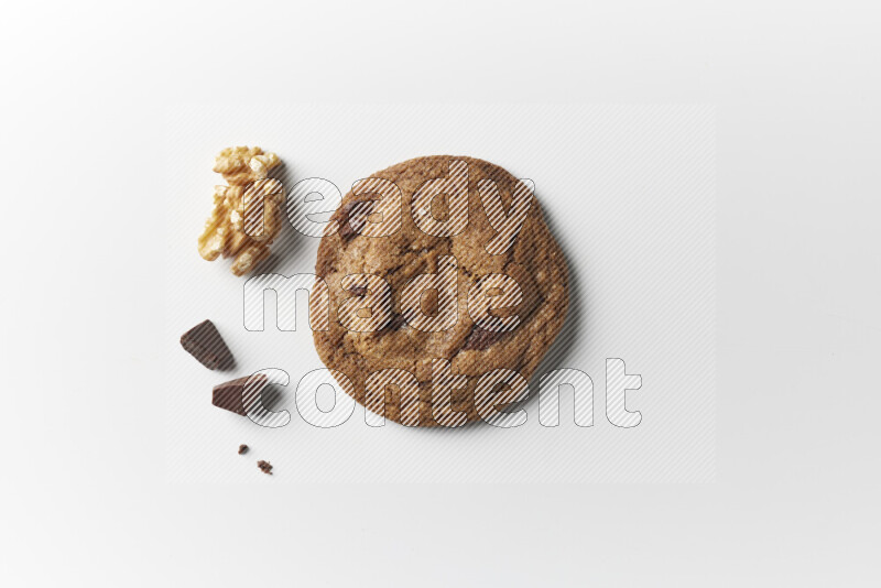 A single chocolate chips cookie with chocolate and walnuts beside it on a white background