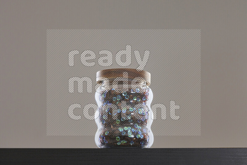 Sequins in a glass jar on black background