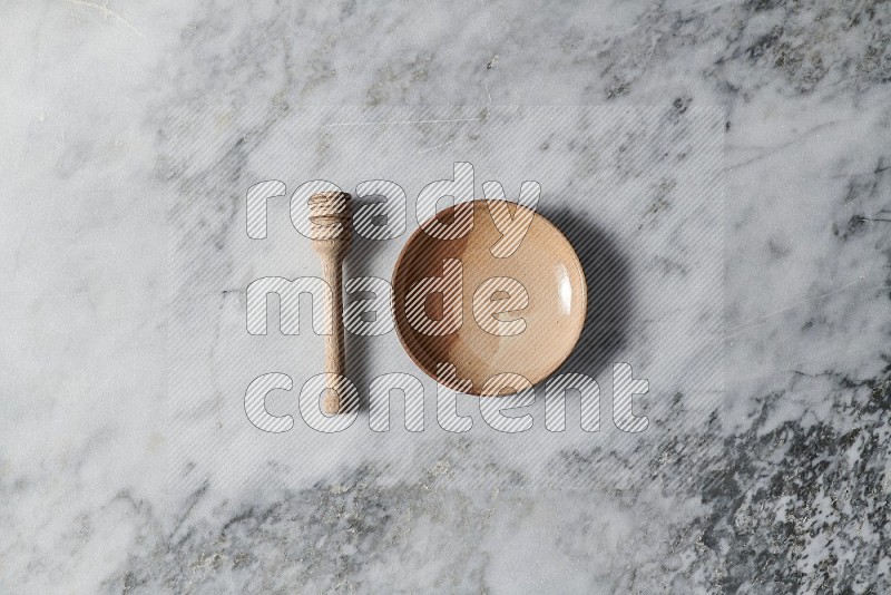Multicolored Pottery Plate with wooden honey handle on the side on grey marble flooring, Top view
