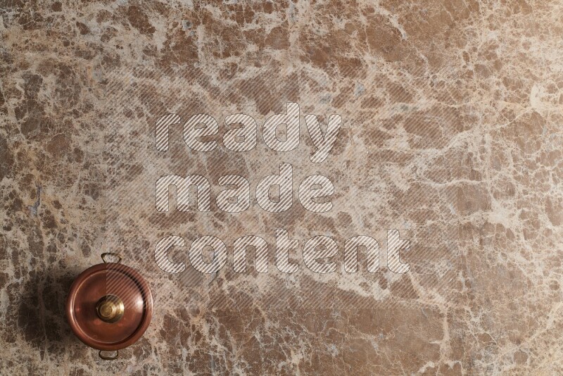 A small copper pot on beige marble background