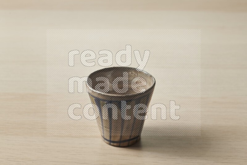 A pottery cup on light wooden background