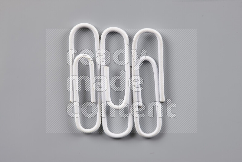 White paper clips isolated on a grey background