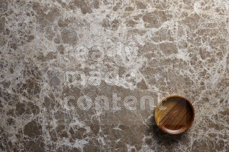 A wooden bowl on beige marble background