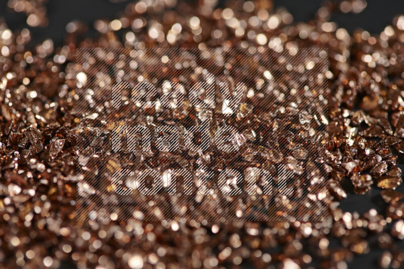 قطع زجاجية برونزية لامعة متناثرة على خلفية سوداء