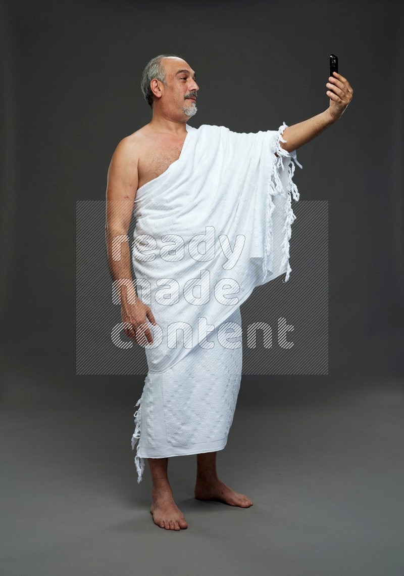 A man wearing Ehram Standing taking selfie on gray background