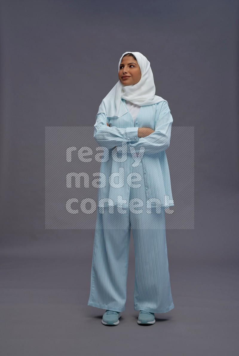 Saudi woman wearing hijab clothes standing with crossed arms on gray background