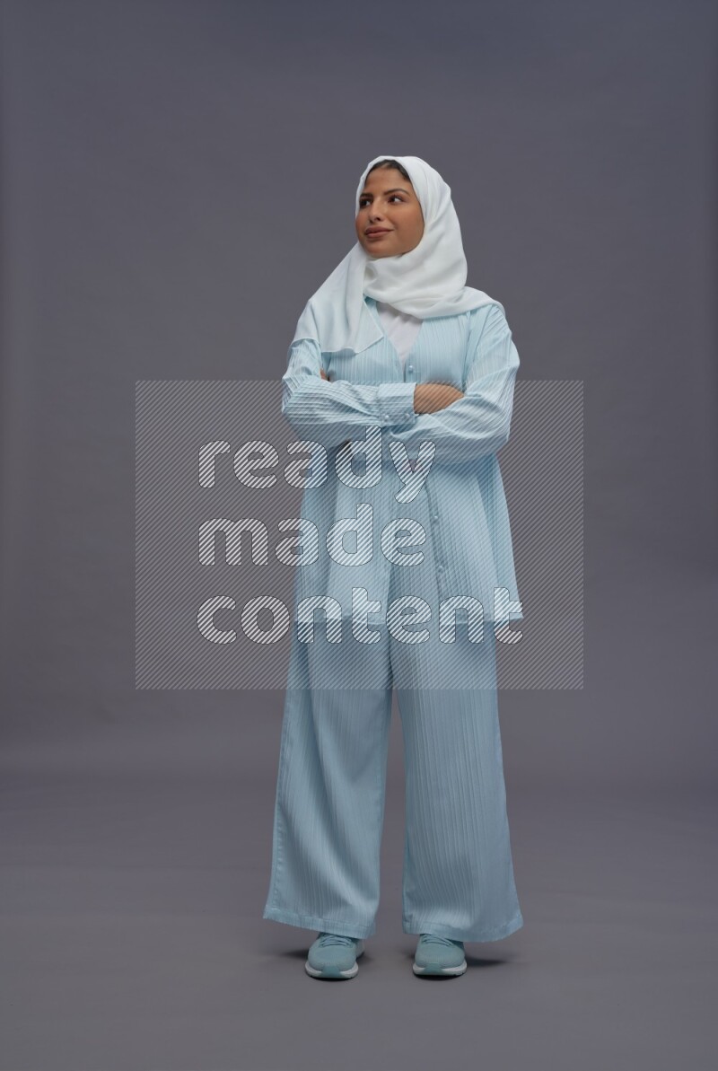 Saudi woman wearing hijab clothes standing with crossed arms on gray background