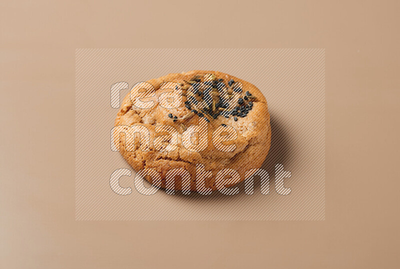 a whole Hasawi cookie with grains on a brown background