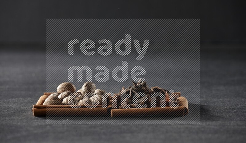 مربعان من أعواد القرفة ممتلئان بجوزة الطيب واليانسون النجمي علي خلفية سوداء